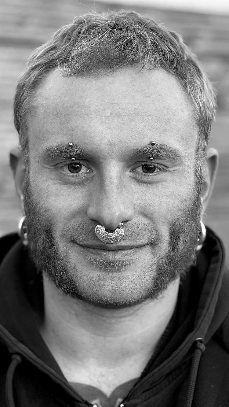 Man with a beard featuring a symmetrical double eyebrow piercing and septum ring.