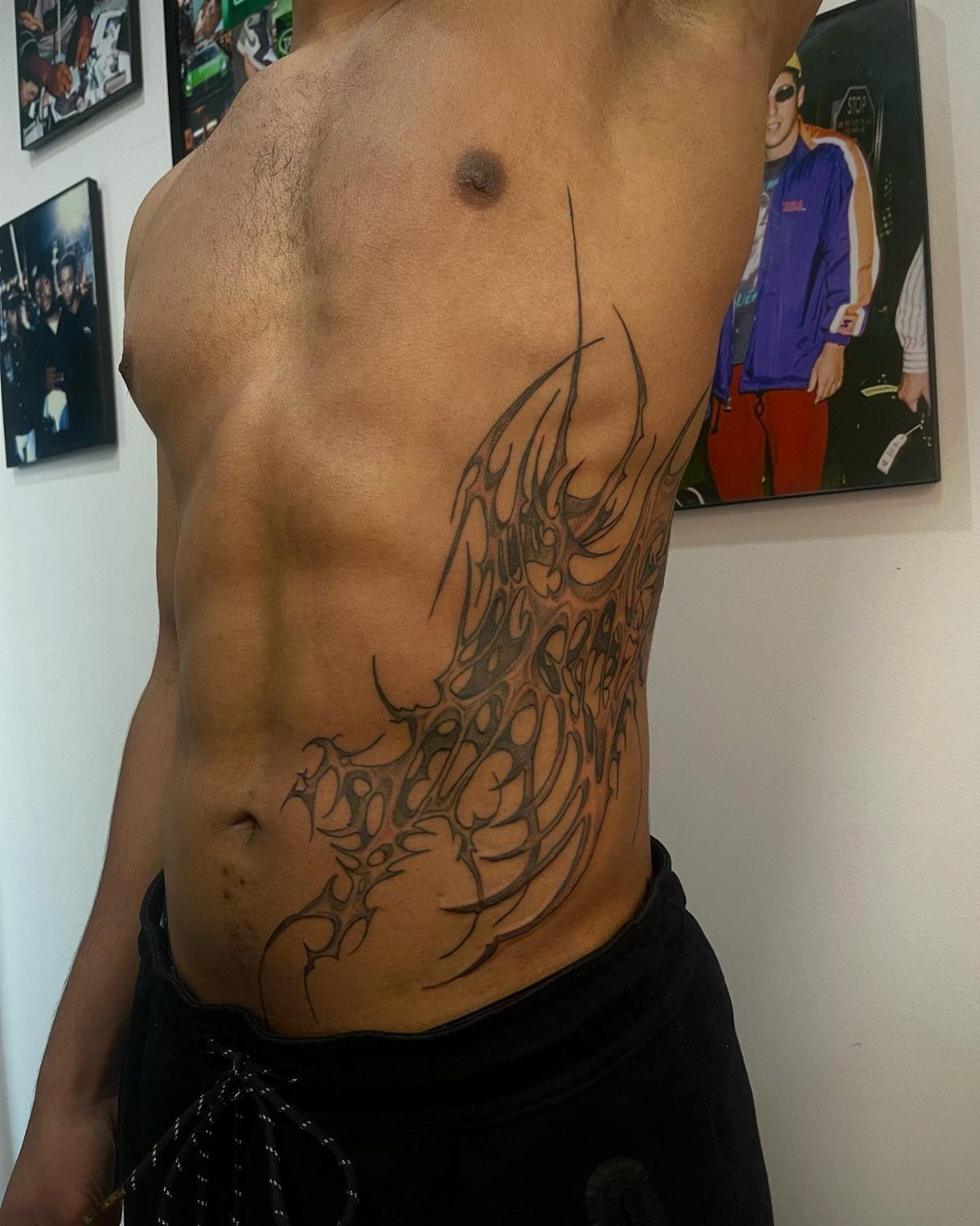 Intricate black tribal tattoo on a man's ribcage and side torso