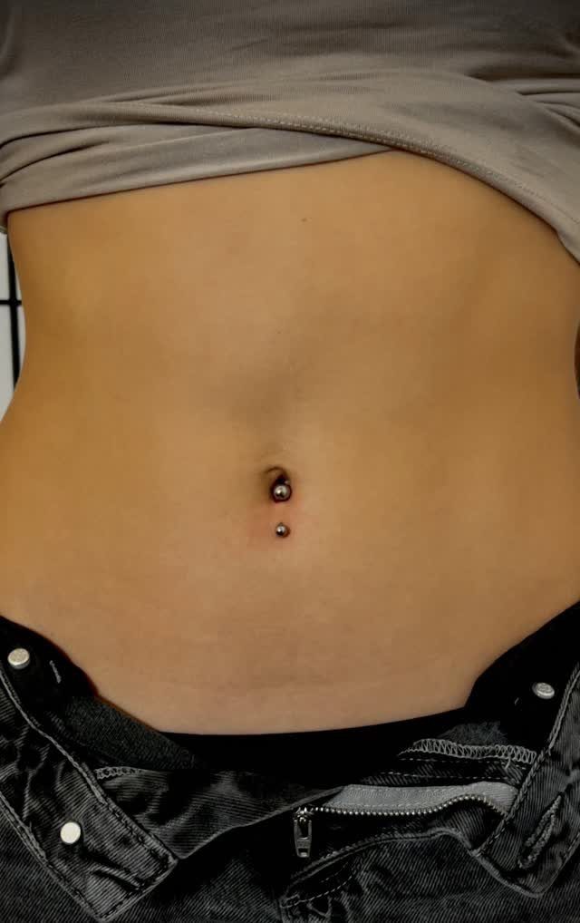 Inverse navel piercing with silver barbell jewelry on a person's belly button.