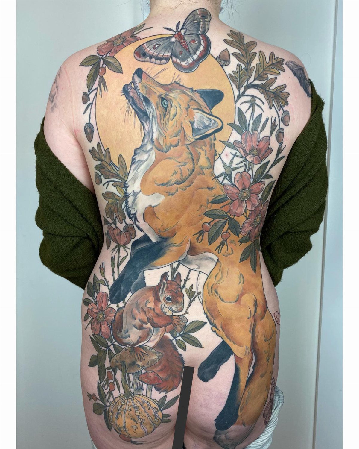 Full back tattoo featuring a fox, squirrel, and butterfly surrounded by nature elements.