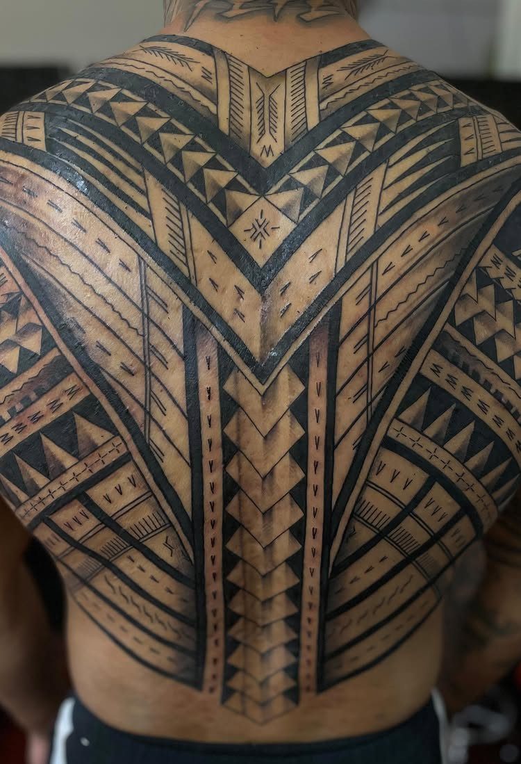 Symmetrical black ink tribal tattoo with geometric patterns covering a person's entire back.