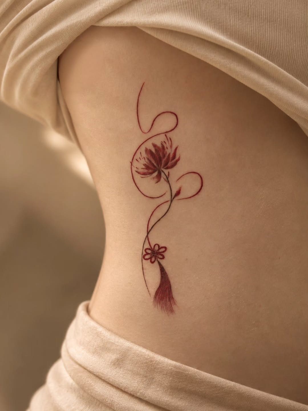 Back Ribs Tattoo Ideas: 7 Designs, Vines to Octopus 7 Red ink floral tattoo with swirling lines on a person's ribcage