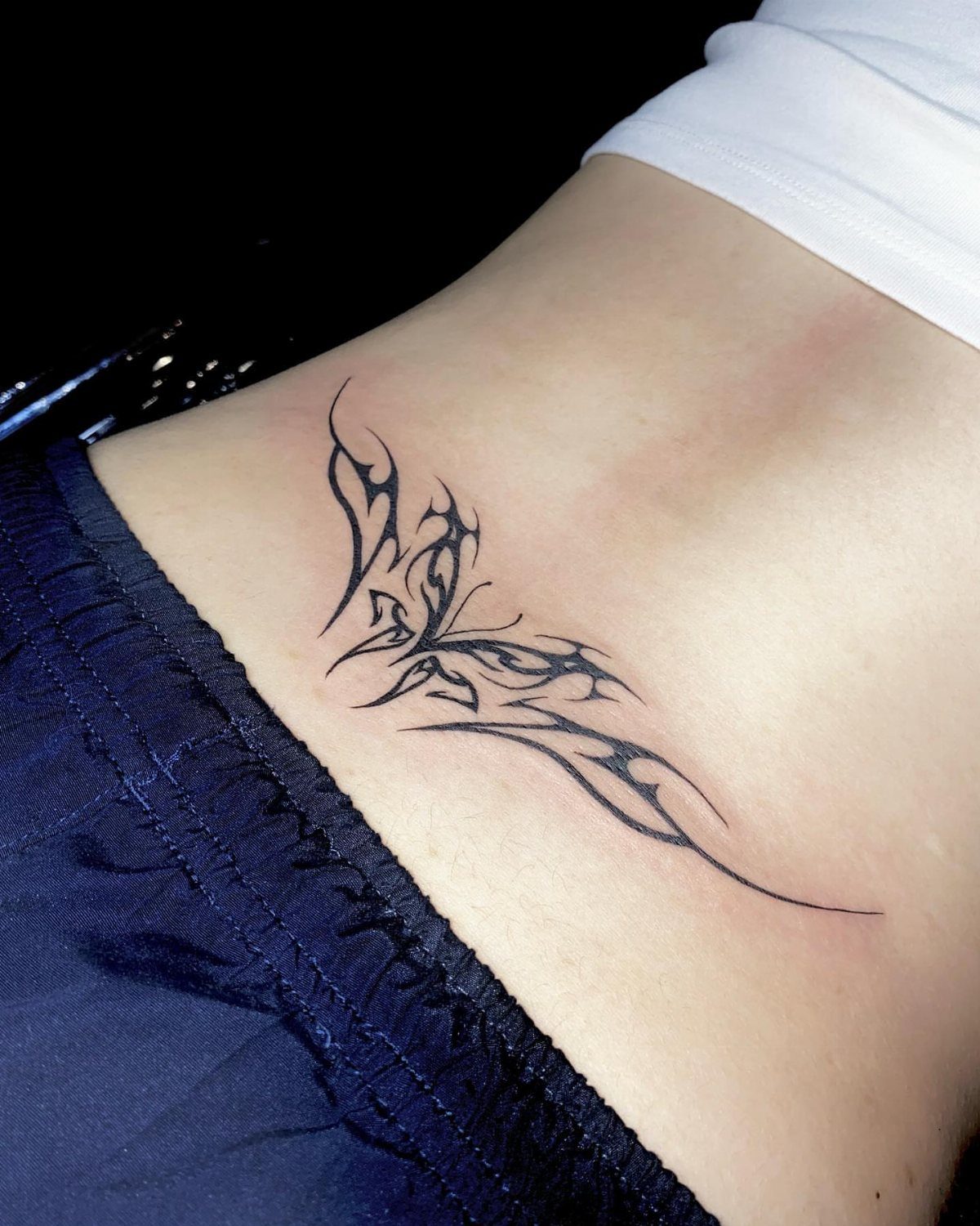 Back Ribs Tattoo Ideas: 7 Designs, Vines to Octopus 5 Tribal tattoo with sharp black lines on a person's lower back and ribs.