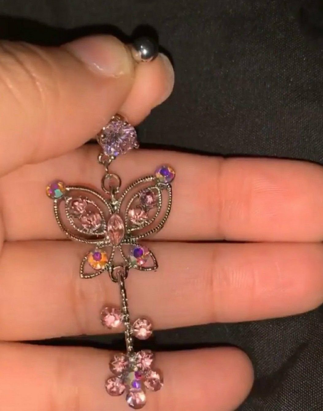 Belly button ring with a pink gemstone and dangling butterfly crystal charm.