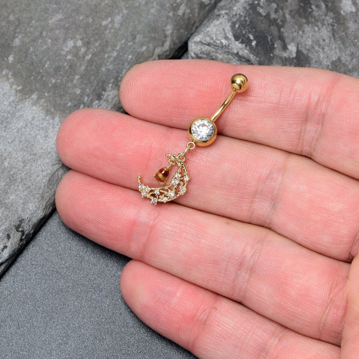 Gold-tone barbell belly piercing with a dangling crystal-encrusted crescent moon charm.