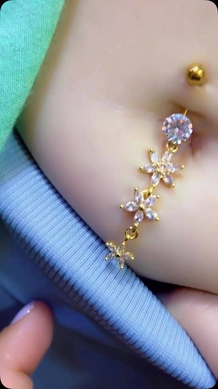 Gold-tone belly piercing with a clear crystal and three dangling flower charms.