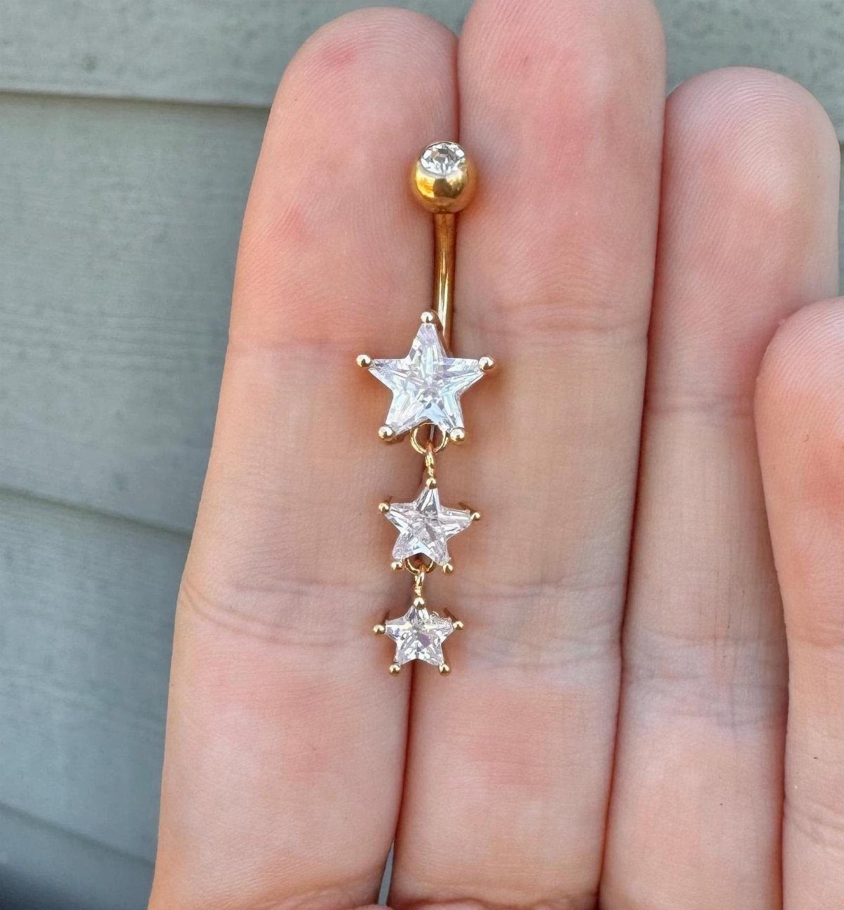 Gold-tone belly piercing barbell with three dangling clear cubic zirconia star charms.