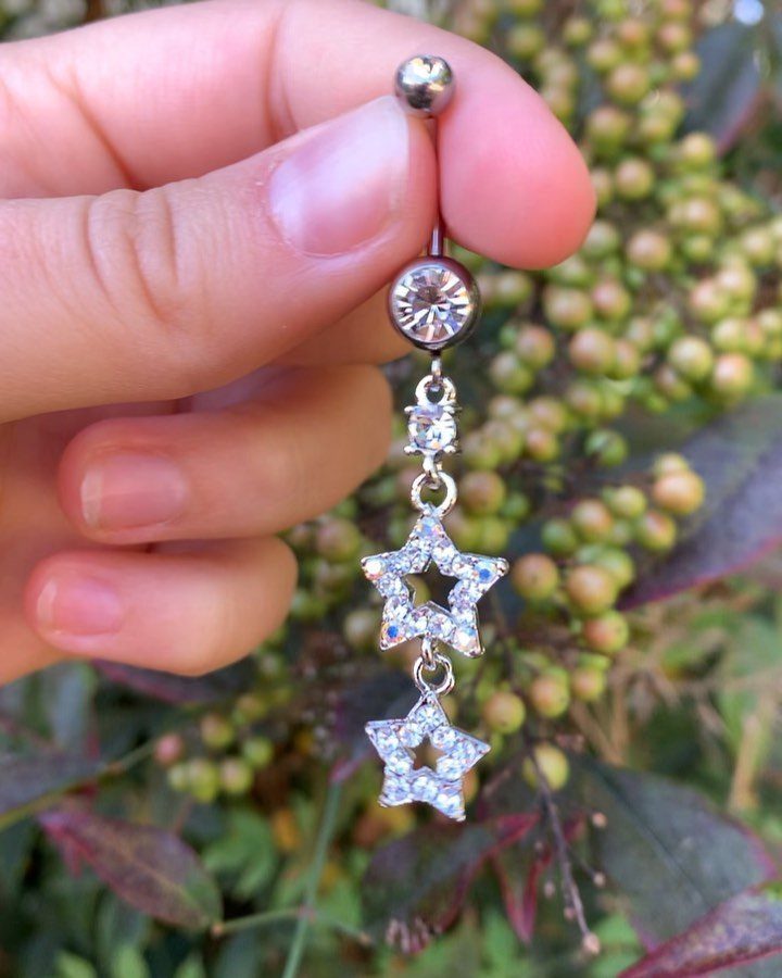 Silver-tone belly piercing barbell with a dangling chain and two crystal star charms.
