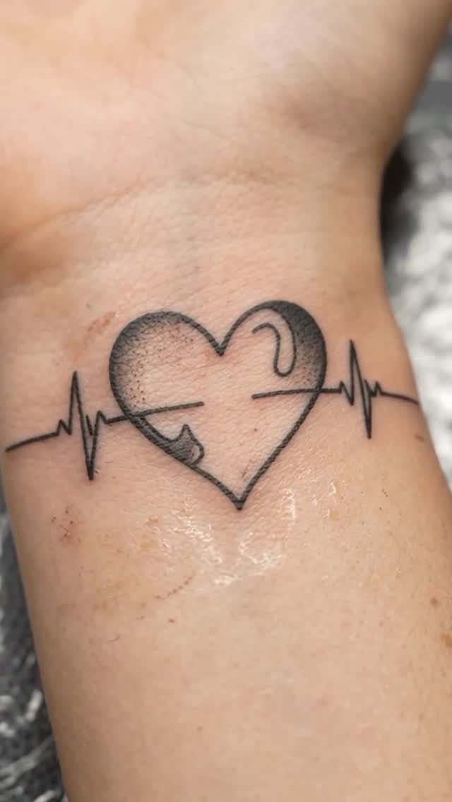 Heart and heartbeat line tattoo on the inner wrist of a person.