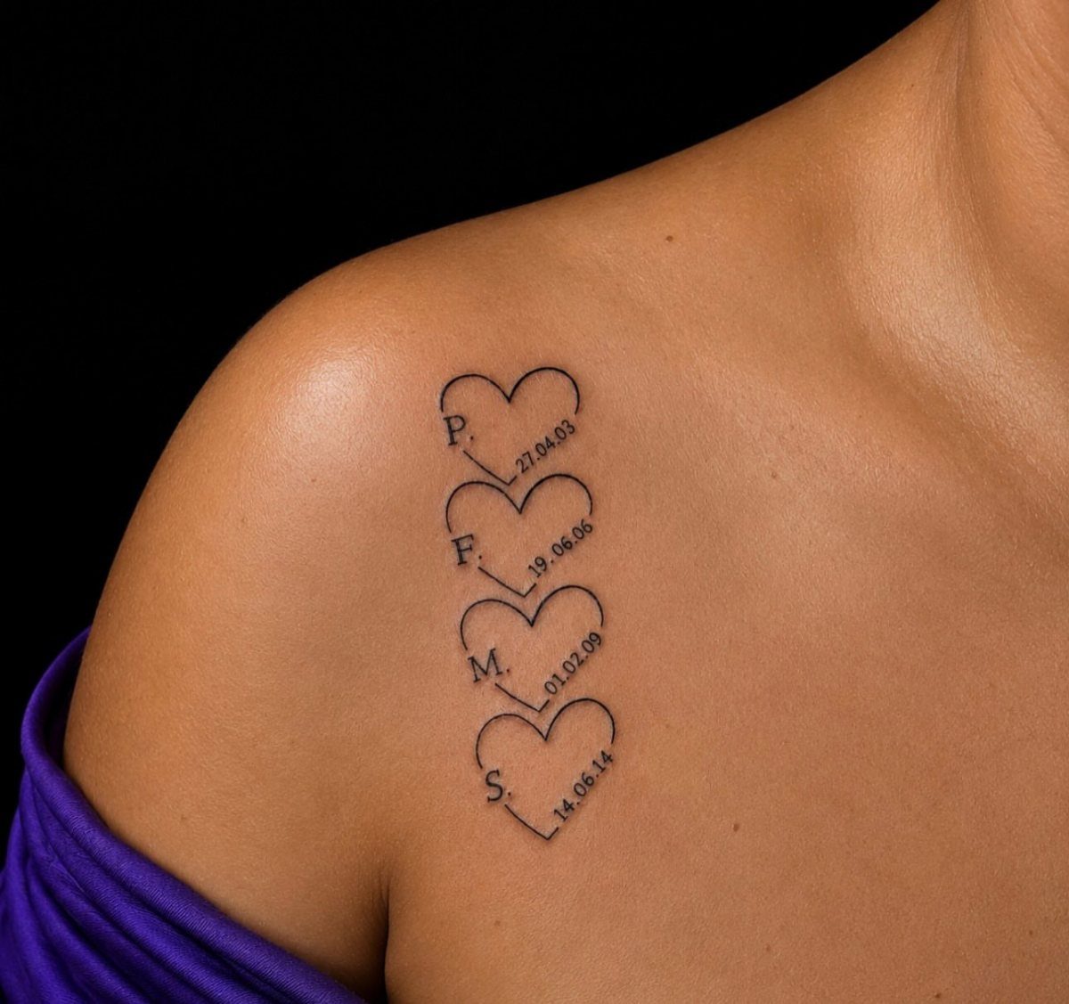 Four heart tattoos on a shoulder with initials and birthdates written beside them.