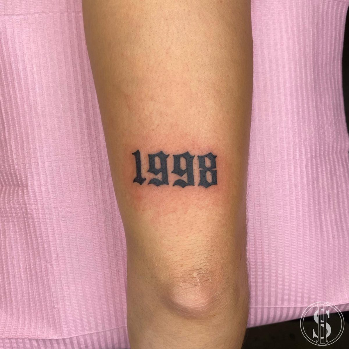 Gothic style tattoo of the year 1998 on a person's lower leg.