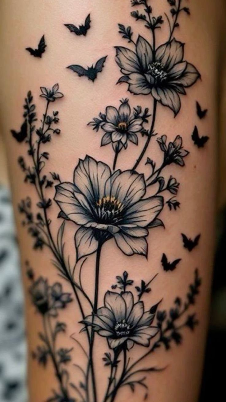 Botanical tattoo with flowers and butterflies in black and grey ink on skin