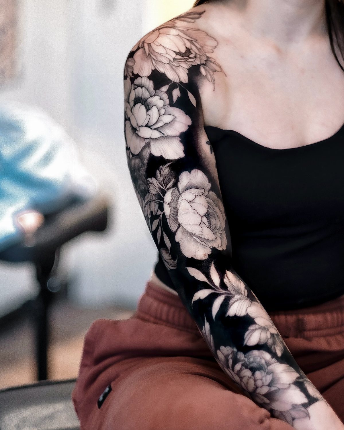 Full arm sleeve tattoo of black and white peonies with deep shading.