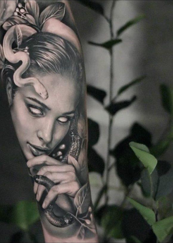 Woman's portrait tattoo with a snake and leaves in black and grey ink.
