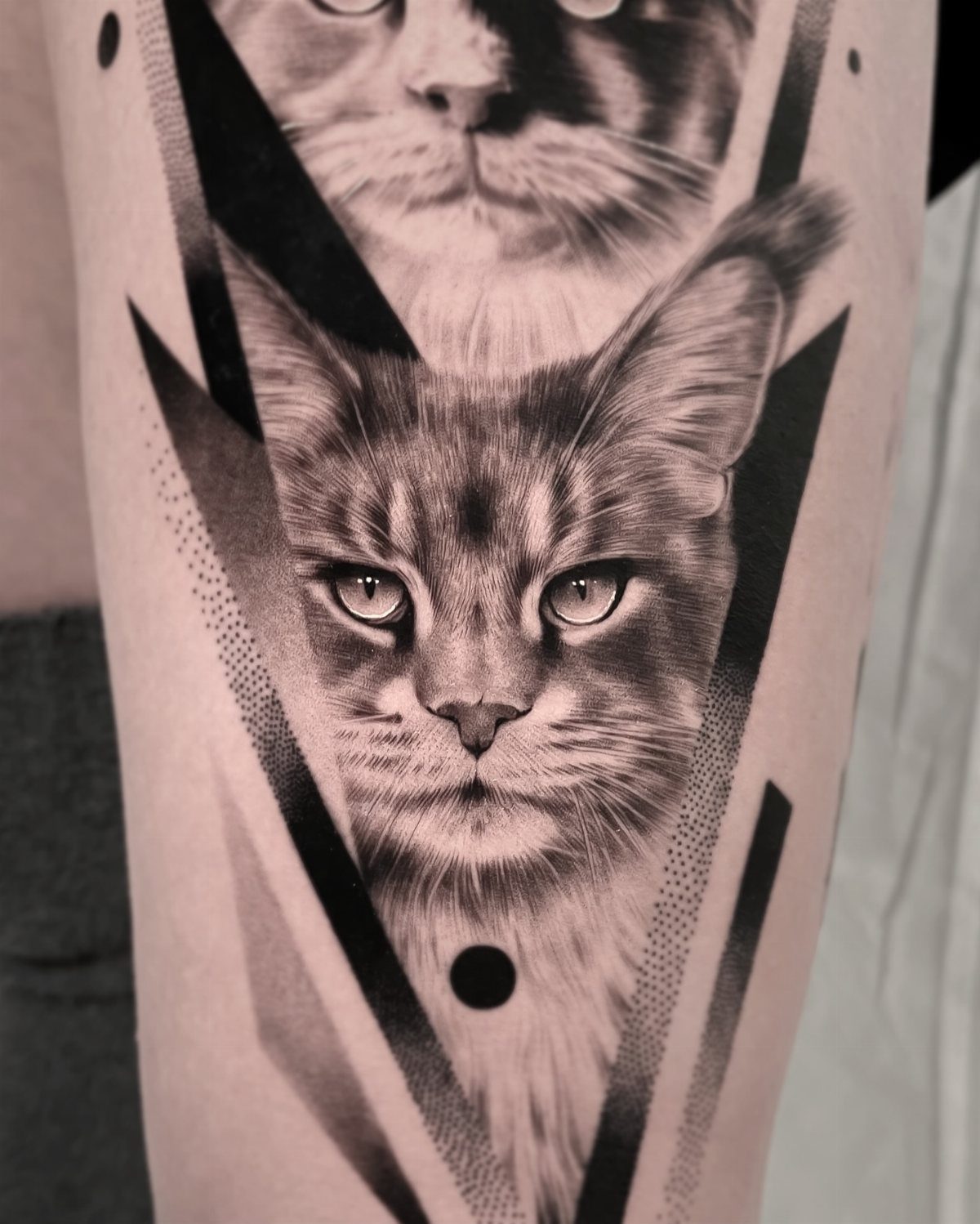 Realistic cat face tattoo with geometric black shapes and dotwork on skin