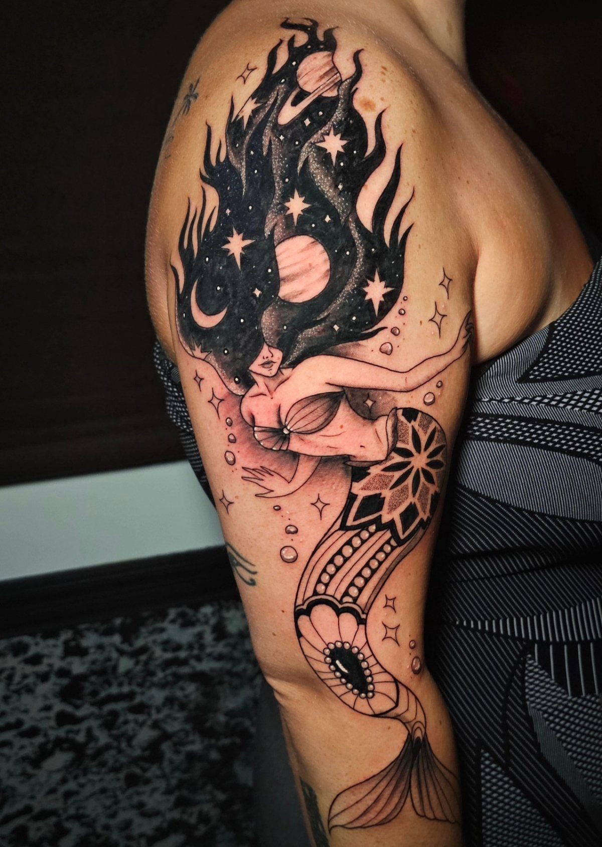 8 Black Mermaid Tattoo Ideas with Afro, Locs and Scales 8 Mermaid tattoo on an arm with cosmic hair containing stars and planets.