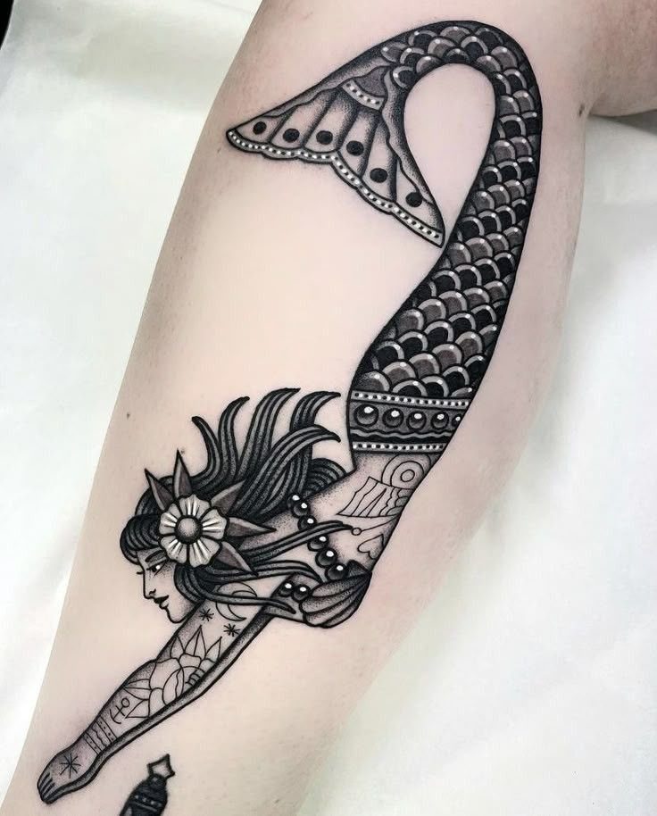 8 Black Mermaid Tattoo Ideas with Afro, Locs and Scales 6 Mermaid tattoo on an arm featuring geometric patterns, stars, and detailed scales.