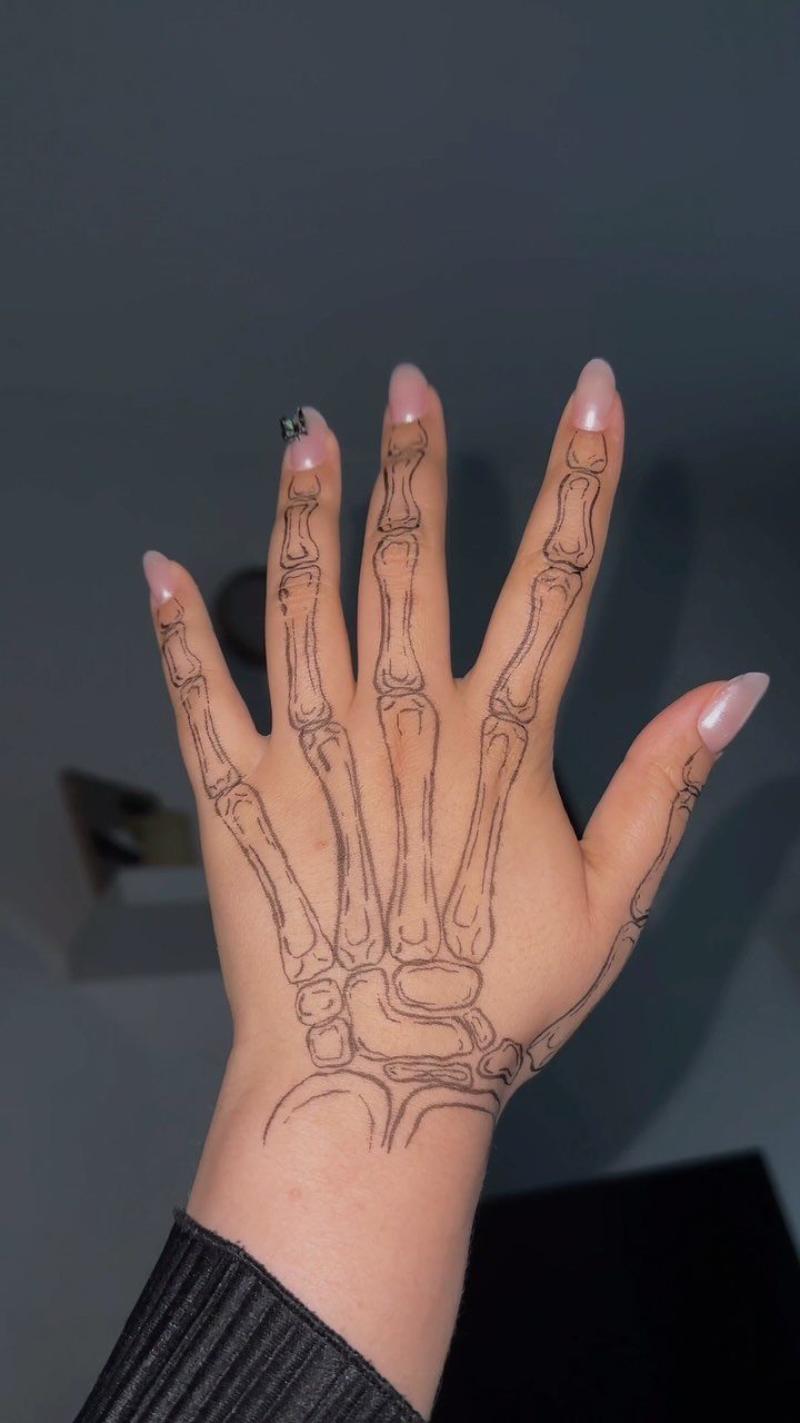 Hand with black ink drawing of skeletal bones on the skin.