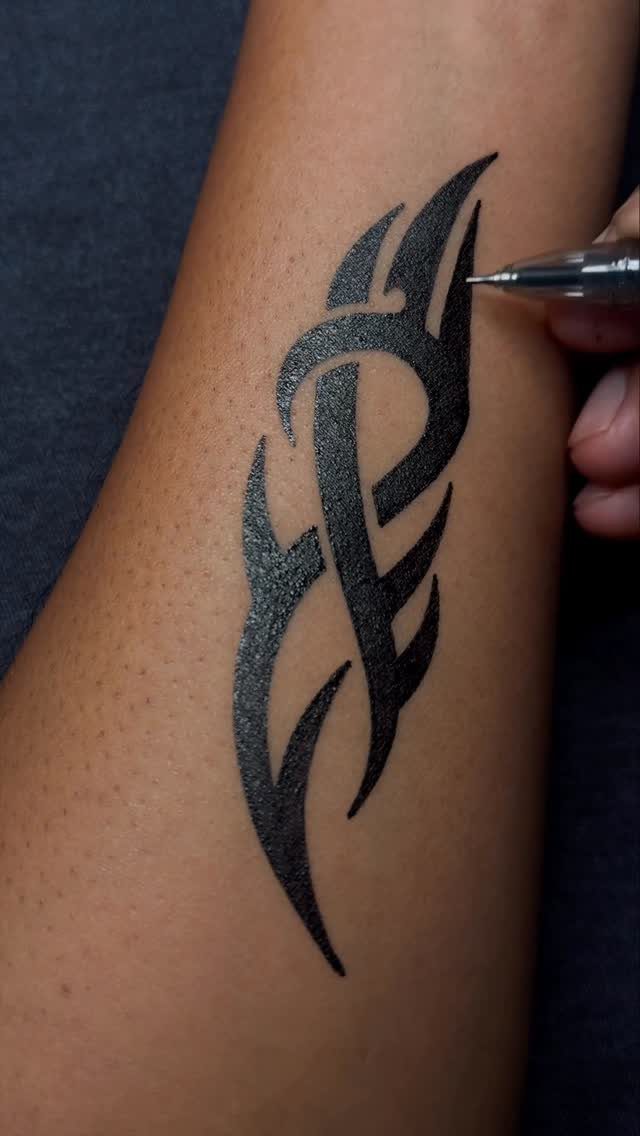 Tribal ink design drawn on a person's arm with a black pen