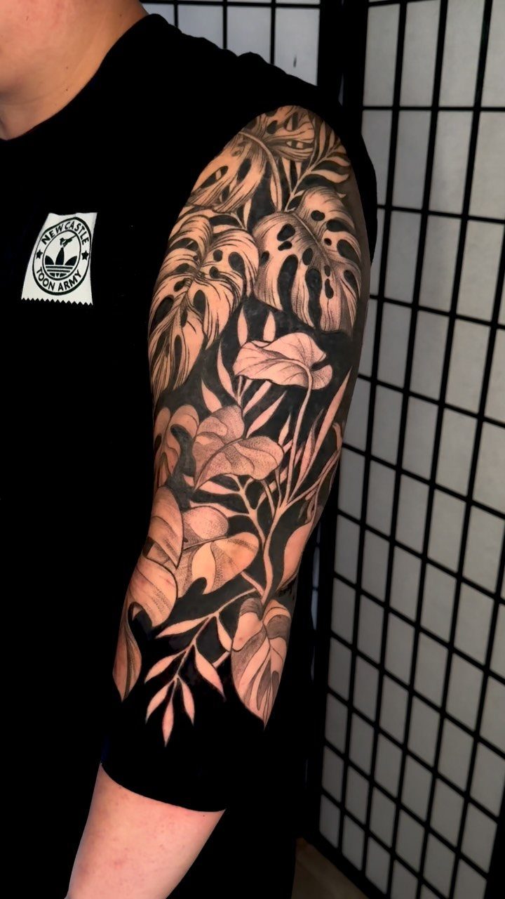 Botanical tattoo sleeve with large tropical leaves on a person's arm
