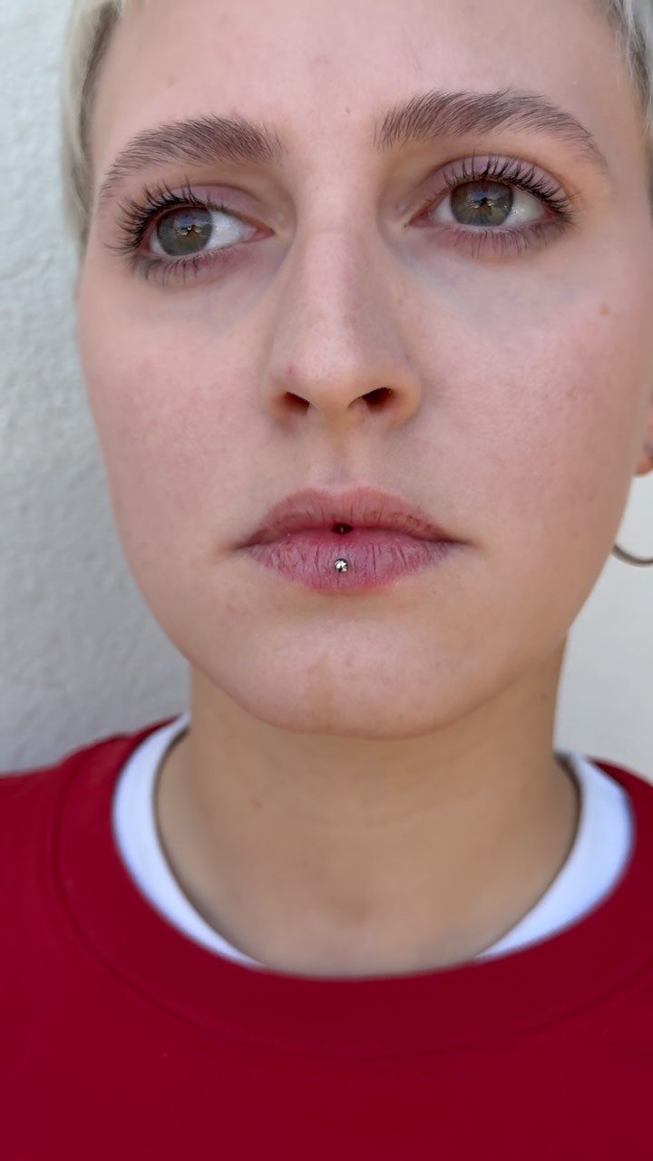 Center Lip Piercing Ideas: 7 Styles to Consider 3 Person with a silver stud piercing in the center of their lower lip.