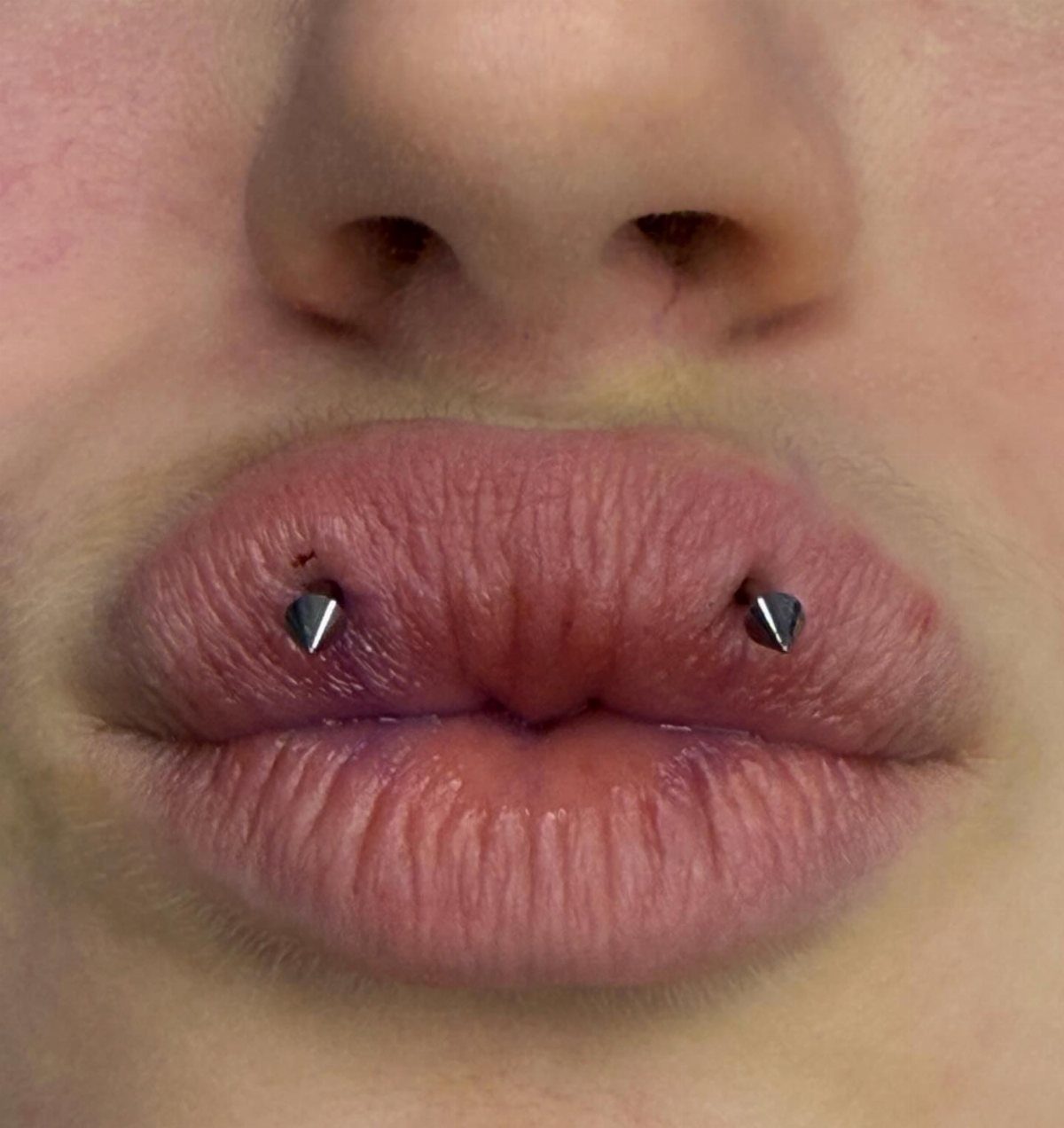 Center Lip Piercing Ideas: 7 Styles to Consider 7 Lips with two silver cone studs pierced symmetrically through the lower lip.