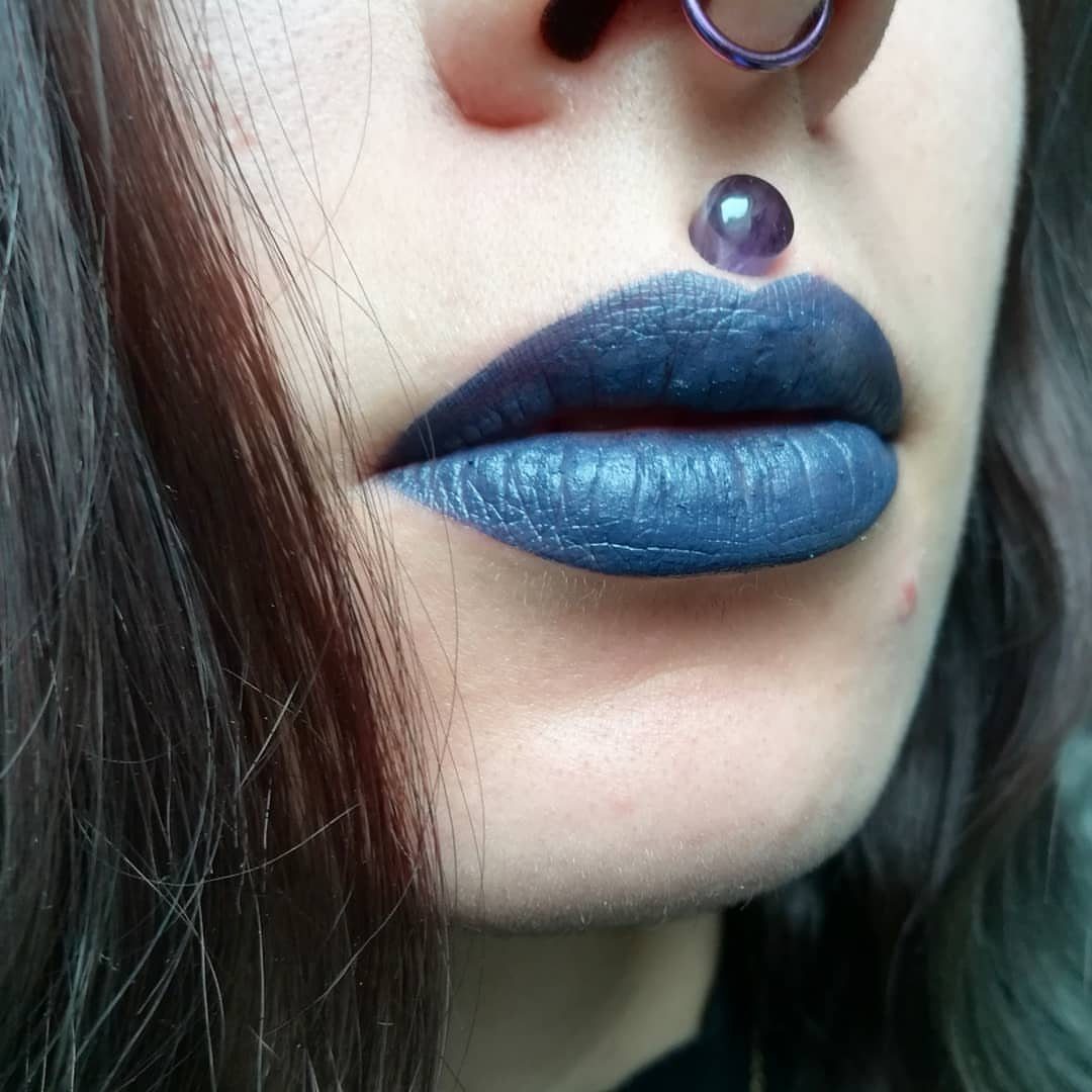 Center Lip Piercing Ideas: 7 Styles to Consider 2 Person with blue lipstick and a purple bead Medusa piercing above the lip.