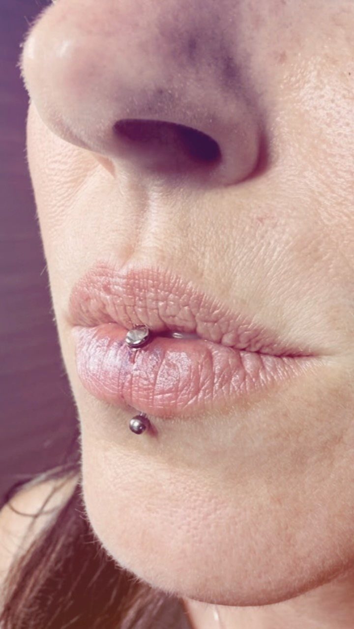 Center Lip Piercing Ideas: 7 Styles to Consider 1 Vertical labret piercing with silver beads on a person's lower lip and chin.