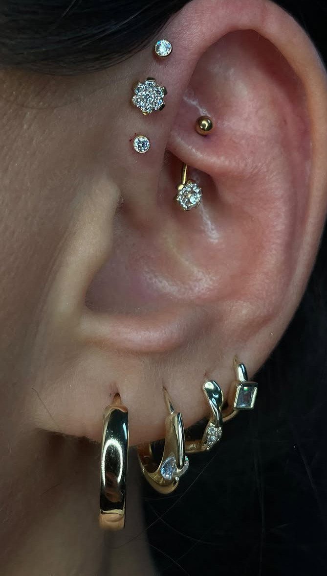 Human ear featuring a triple forward helix piercing with gold and diamond studs.