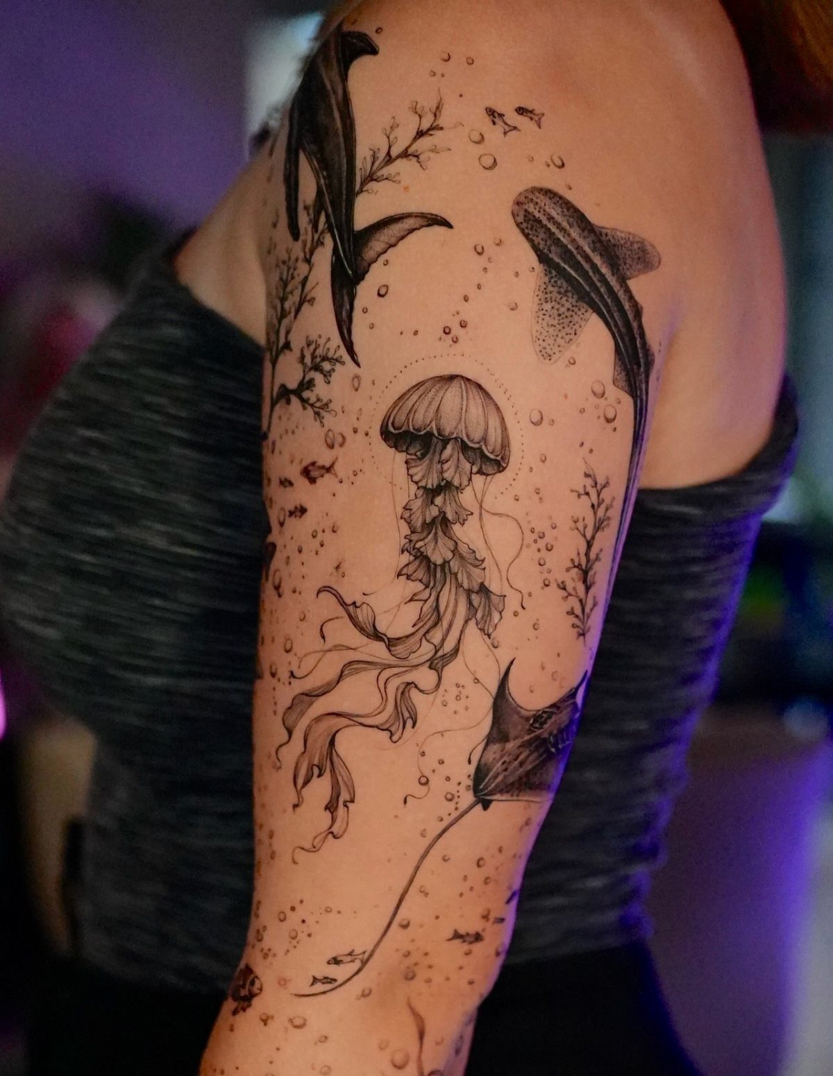 Black ink marine tattoo on an arm featuring a jellyfish, whale, and stingray.