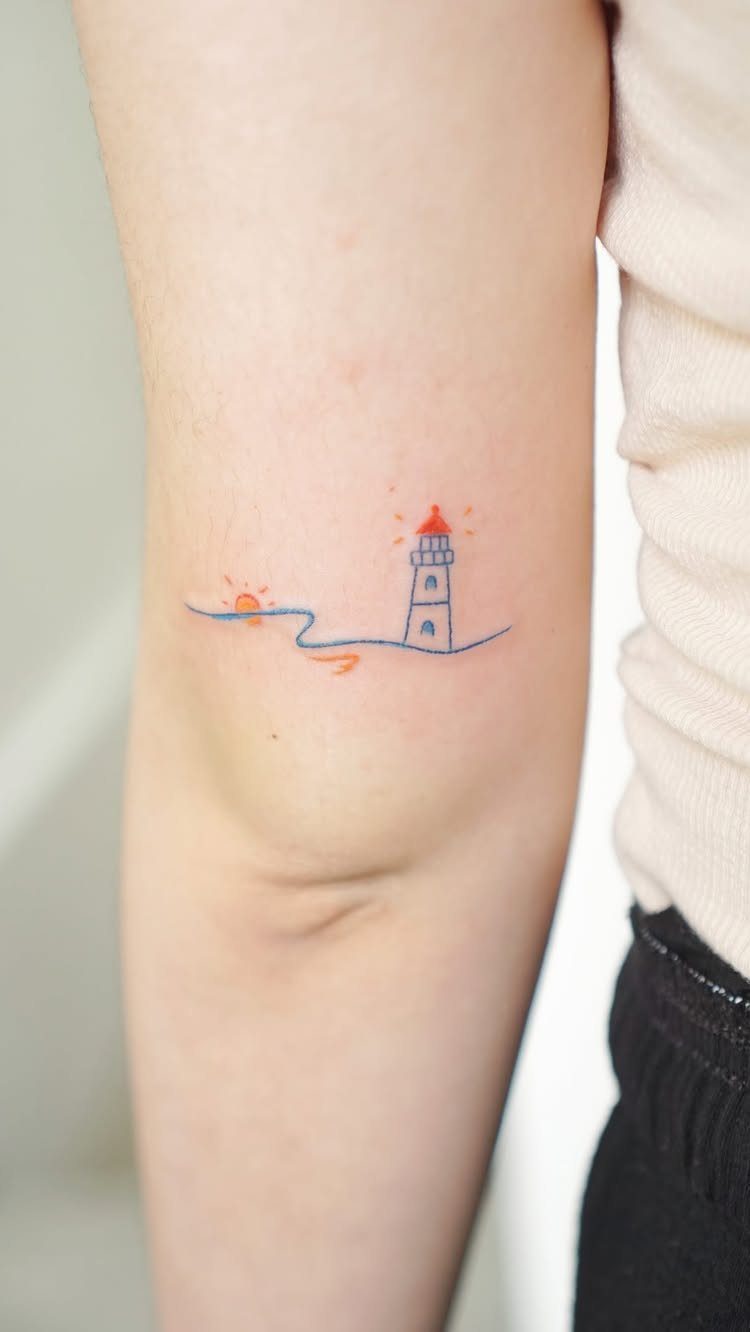Minimalist lighthouse and sun tattoo on a person's inner arm with blue waves.