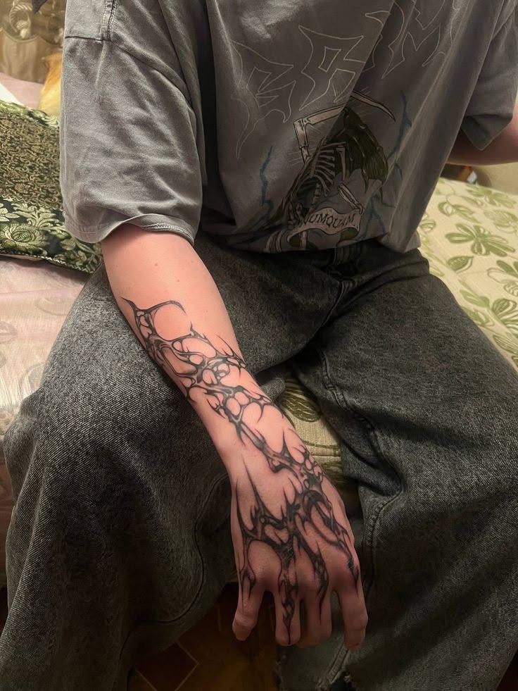 Hand and forearm with a black ink web-like cybersigilism tattoo.