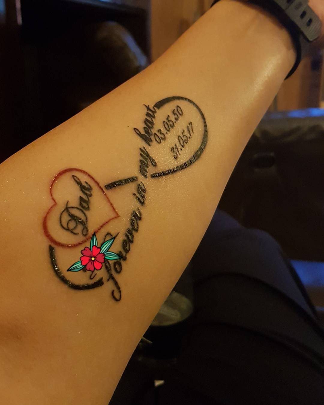 Infinity symbol tattoo on forearm with a red heart containing the word Dad