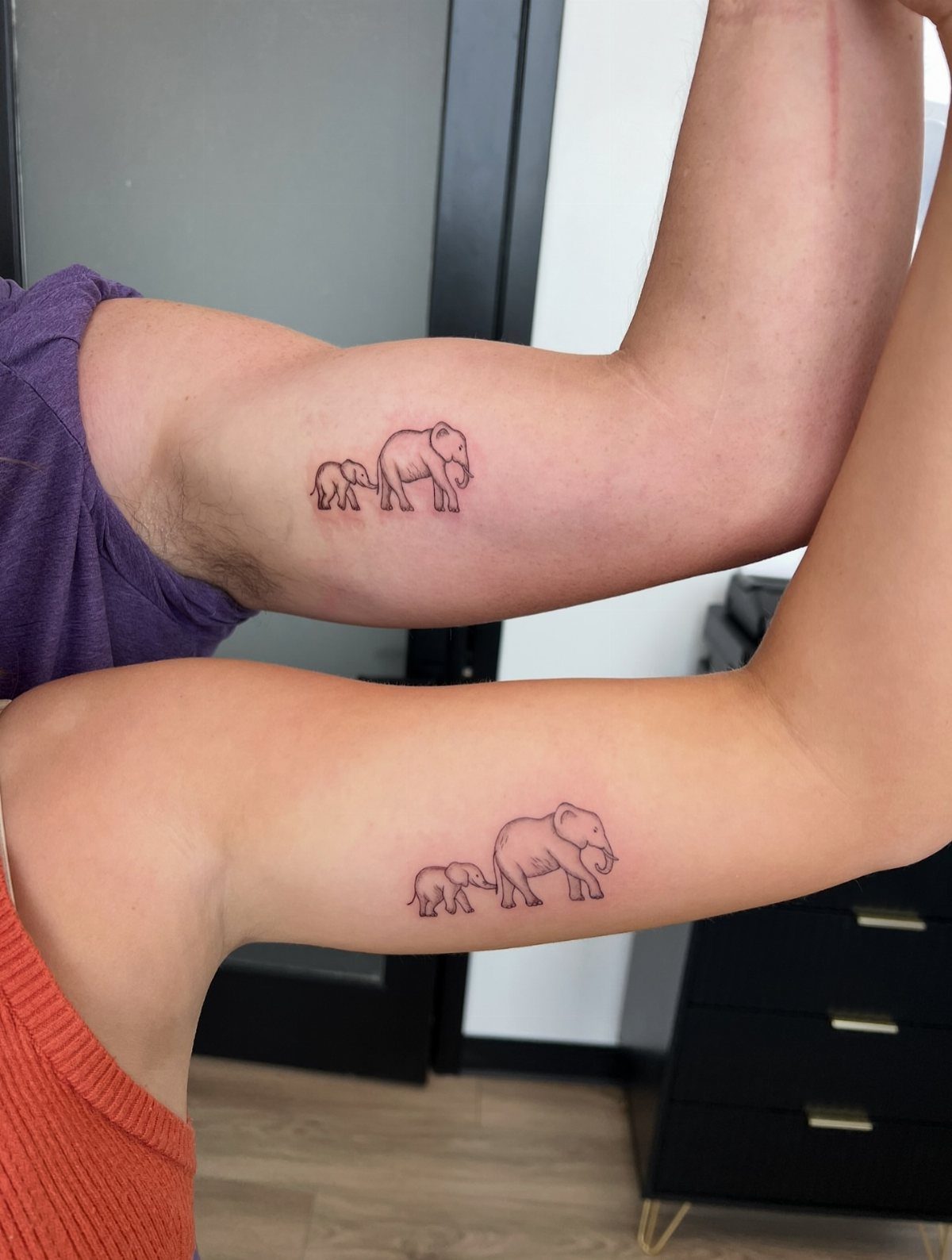 Matching elephant tattoos of a parent and baby on two different forearms.