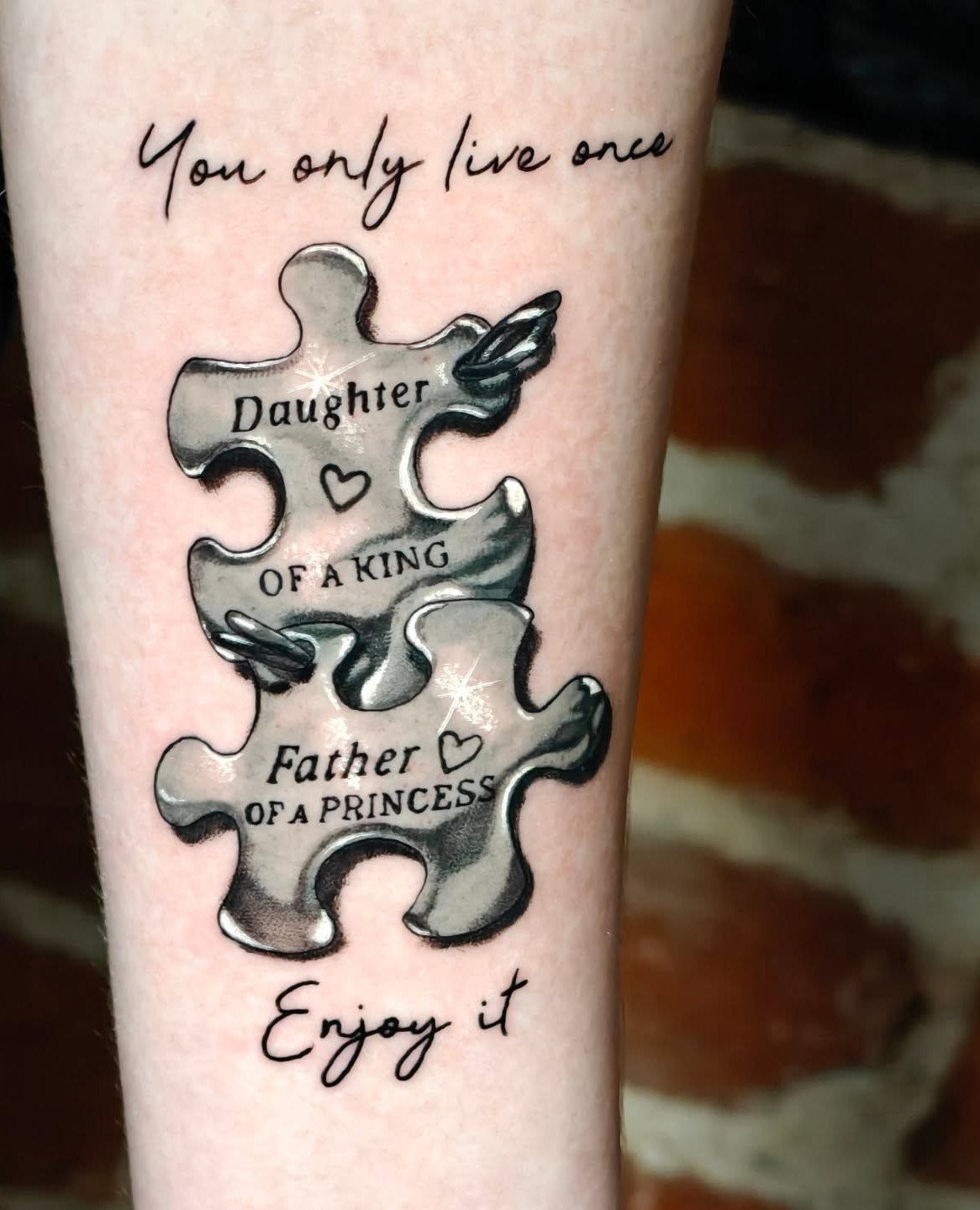 Interlocking puzzle piece tattoos on skin with text about father and daughter.