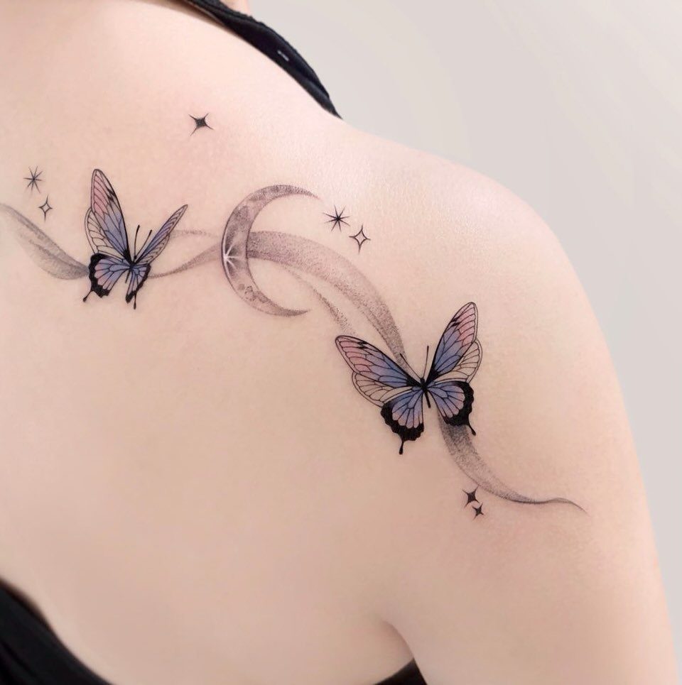 Crescent moon and stars tattoo with blue butterflies on a person's shoulder