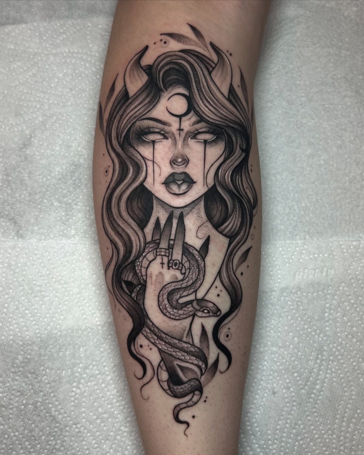 Tattoo of a horned woman with a serpent coiled around her hand.
