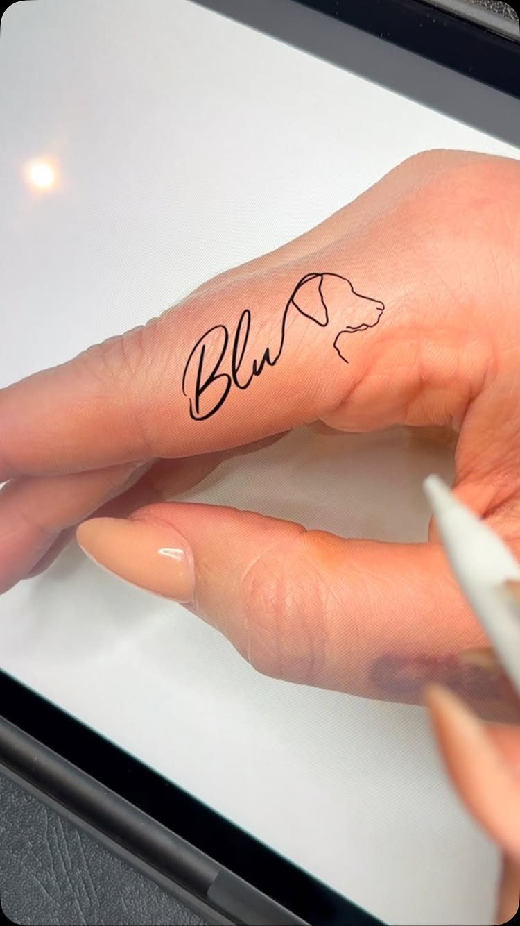 Minimalist dog profile and name Blu tattoo on a person's finger