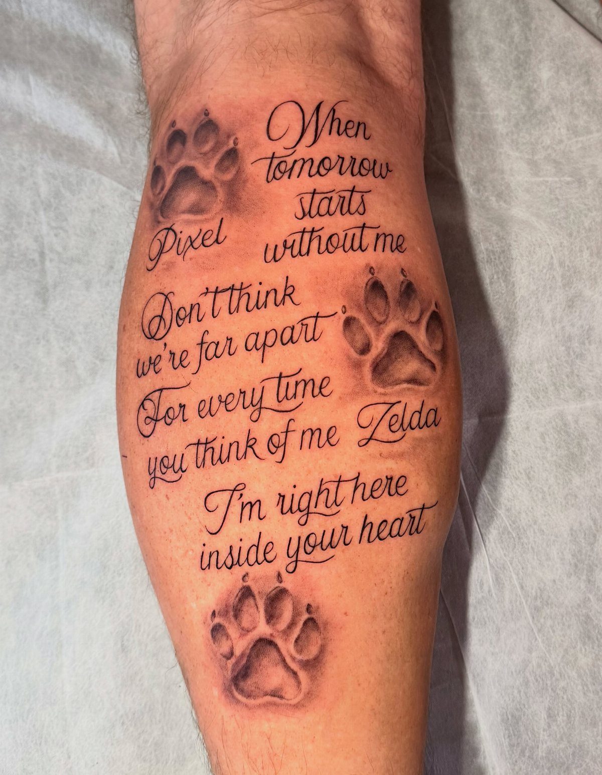 Dog memorial tattoo with three paw prints and a heartfelt poem on a leg.