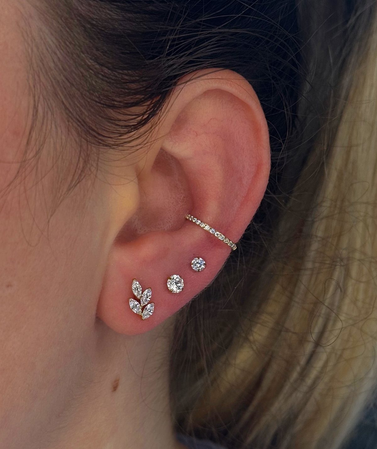 12 Ear Piercing Combo Ideas for Every Style 1 Ear with a crystal conch piercing and a trio of sparkling lobe studs.