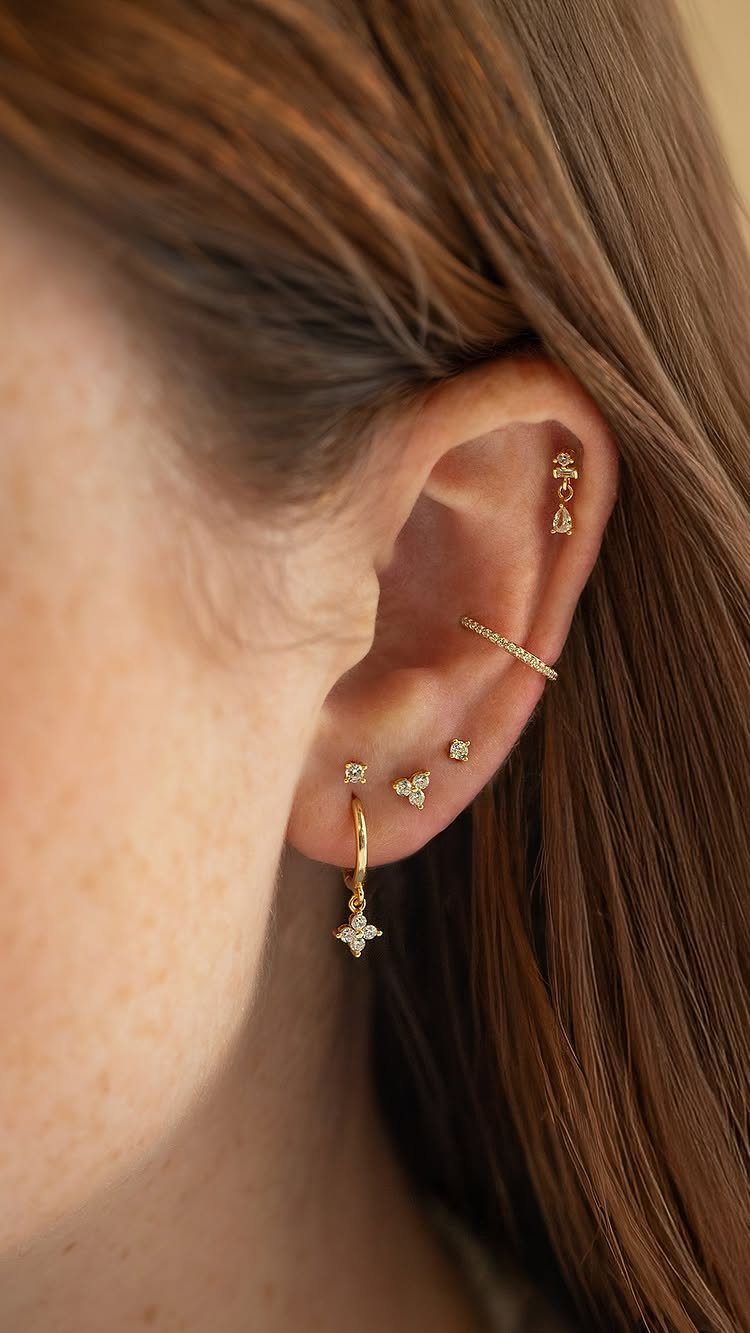 12 Ear Piercing Combo Ideas for Every Style 6 Ear with gold jewelry including a star dangle, lobe studs, and helix bar.