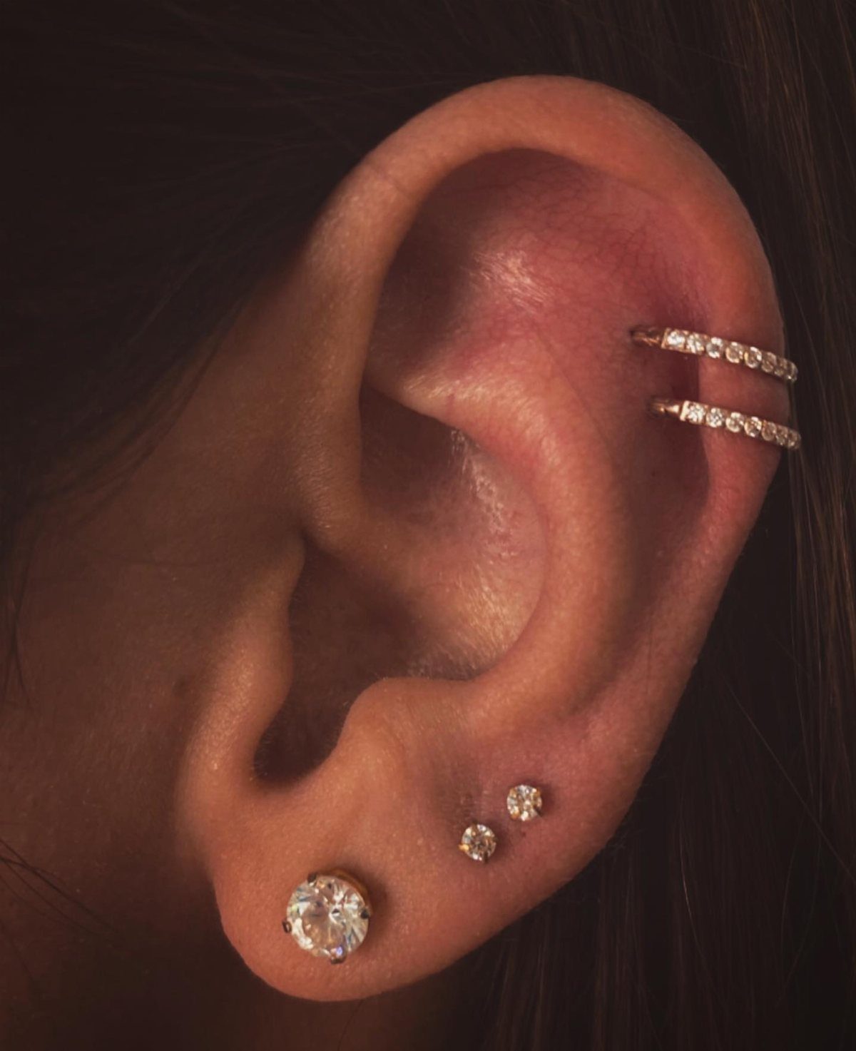 12 Ear Piercing Combo Ideas for Every Style 7 Ear with three lobe diamond studs and two diamond helix bars.