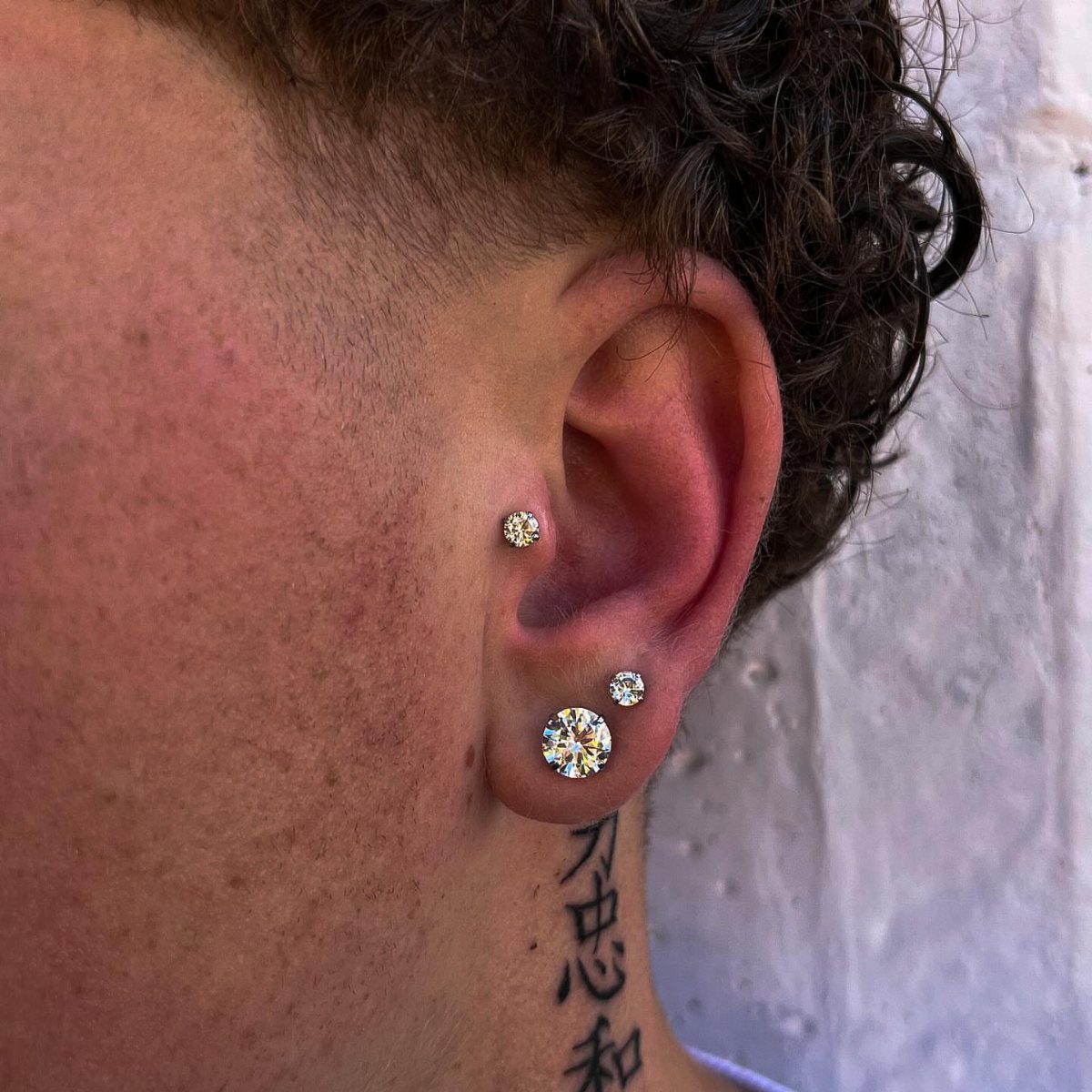 12 Ear Piercing Combo Ideas for Every Style 8 Ear with diamond studs in the tragus and a double lobe piercing setup.