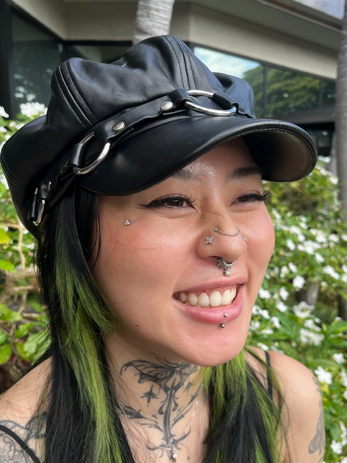 Person with multiple face piercings including a high nostril stud and septum ring.