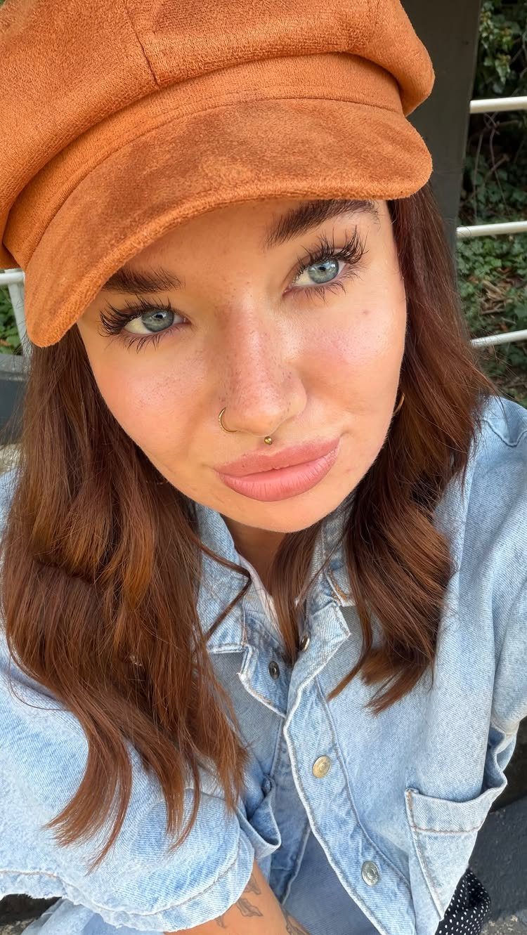 Woman with blue eyes wearing an orange cap and a philtrum lip piercing.