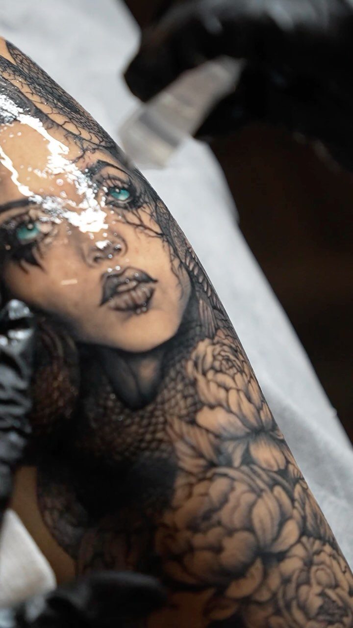 Medusa tattoo with snakes for hair and large peonies on a person's skin