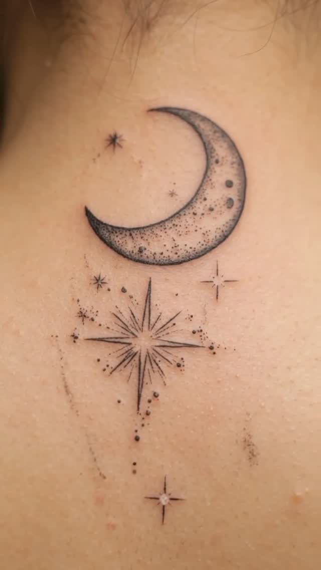 Crescent moon tattoo with small stars and dots on fair skin.
