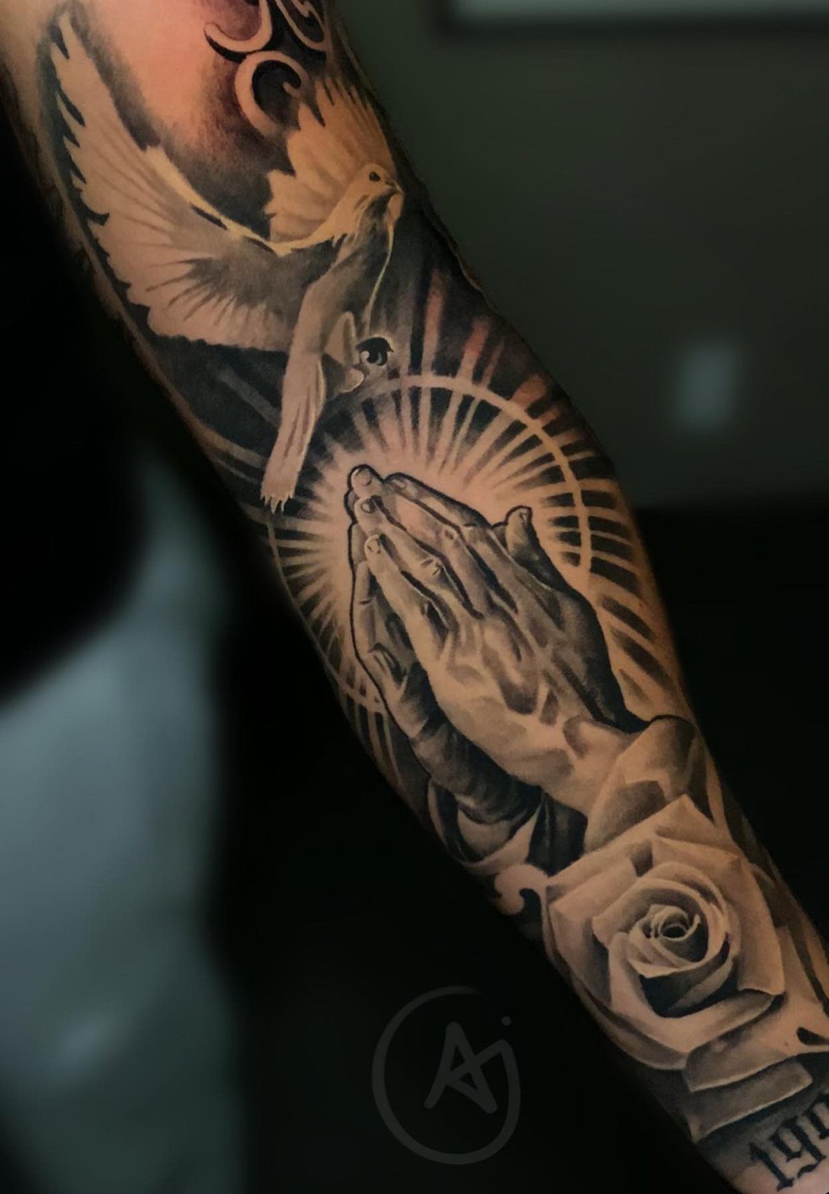 Praying hands tattoo with a radiating halo, white dove, and a rose.