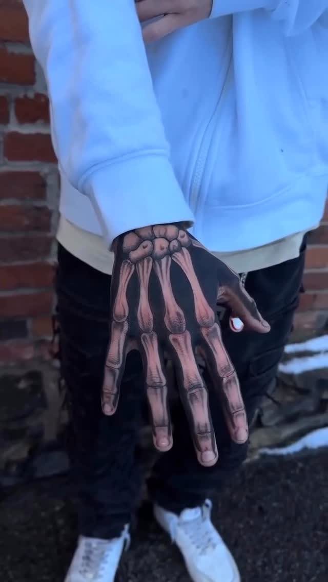 Skeleton hand tattoo covering the back of a hand and fingers on a person.