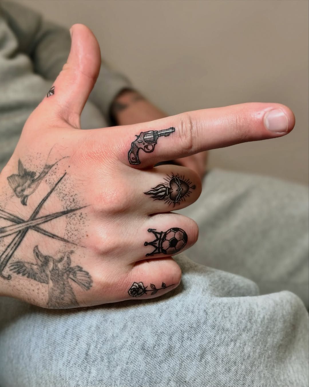 Hand with various black ink tattoos on each finger and the back of hand